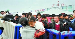 广州火车站广场人多拥挤，一名旅客抱起女儿越过防护栏将她送入候车点。 记者莫伟浓摄