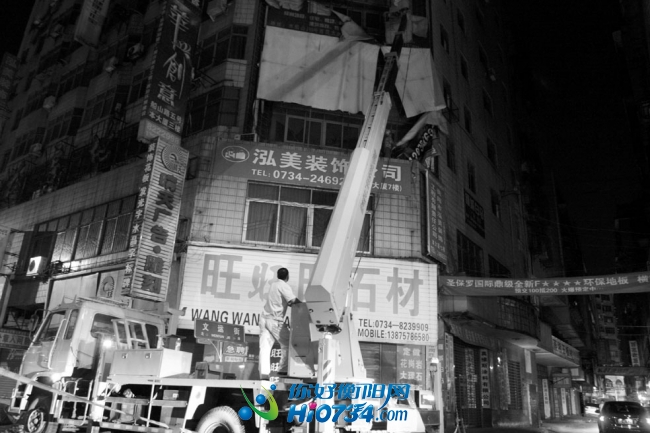 动用大型升降机拆除破损广告。 王平   摄