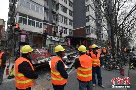 资料图:2月21日,北京市西城区白纸坊西街上,聚集了不少工程车和执法人员,随着对大清花饭店门前避风格的拆除,拉开了白纸坊地区2017年“开墙打洞”整治行动的序幕。由于历史原因白纸坊西街南侧不少居民楼底墒形成了大量违法建设。金硕 摄