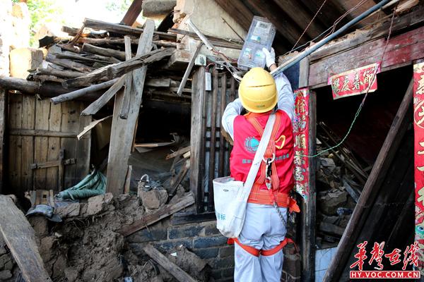 供电公司员工在归阳镇毛坪村蔬菜组处理倒塌房屋上的电表，防止发生触电事故。（摄影：彭智勇）.JPG