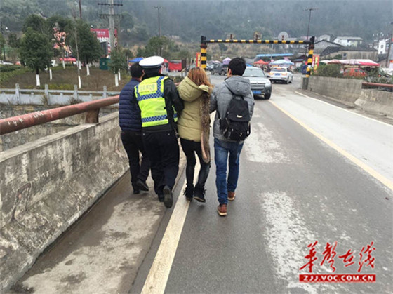 民警将欲跳桥女游客抱下护栏回到桥面，行人帮忙扶至路边.jpg