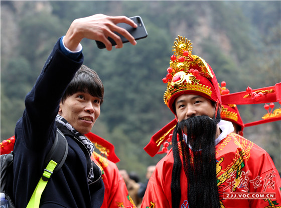 在张家界百龙天梯，一名游客与财神合影 吴勇兵摄.jpg